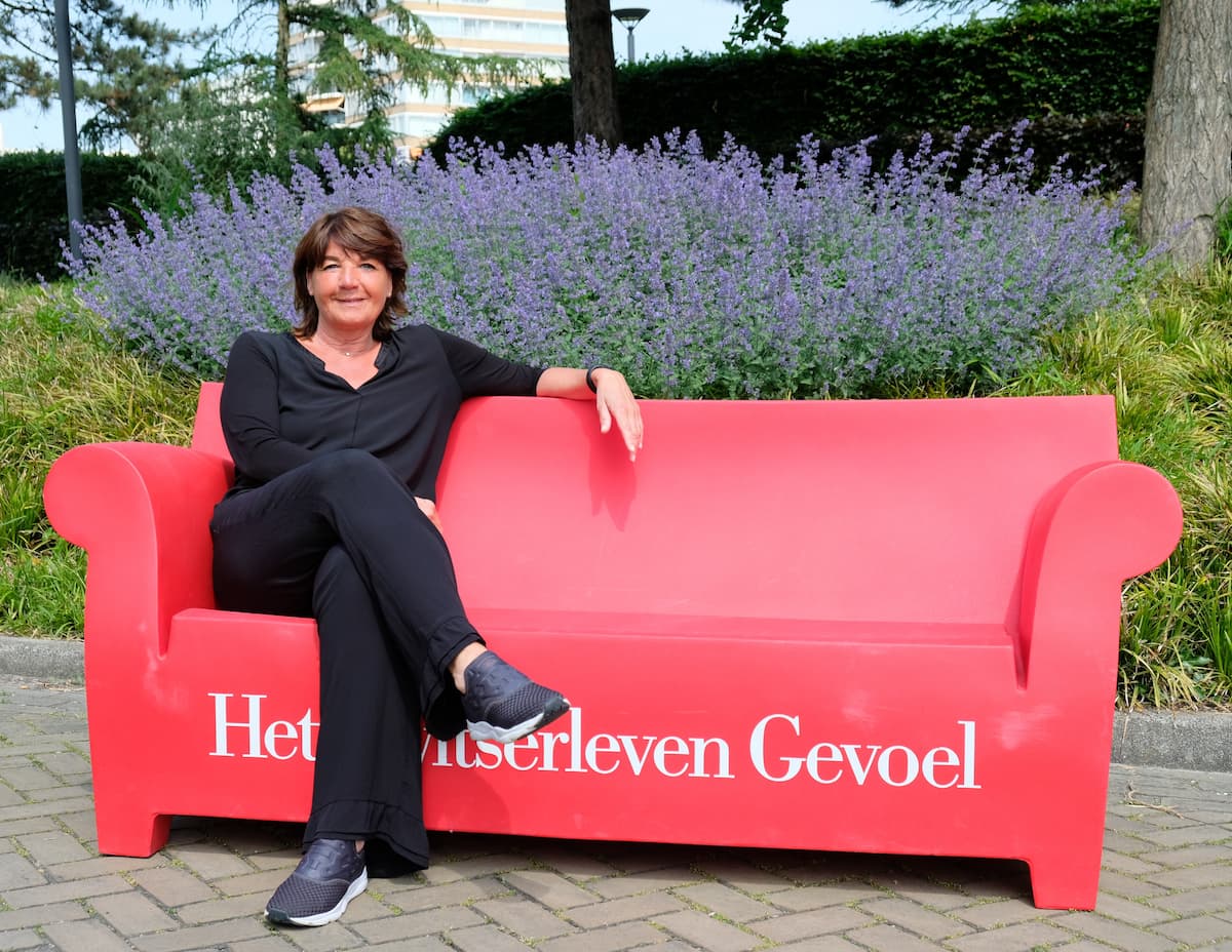 Brand manager Ilse van der Gaag sitting on a red Zwitserleven branded couch