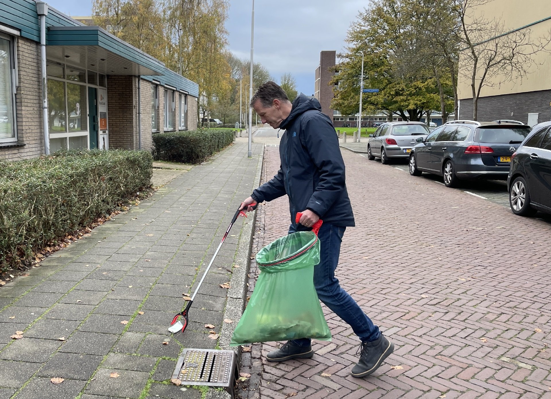 Man raapt afval met een knijper